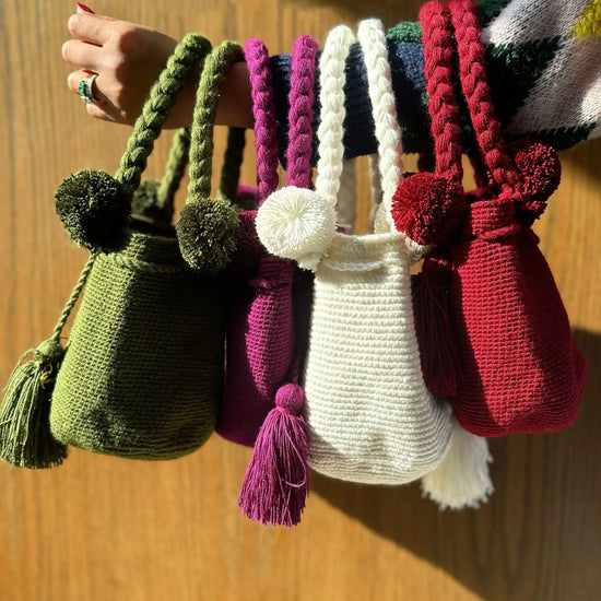 Colorful crochet bags with braided straps, pom-poms and tassels, made in Colombia by Wayuu artisans
