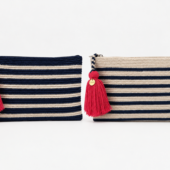 Two woven zip pouches with red & pink tassels, shown side by side on a white background. The left pouch is navy blue & has cream horizontal stripes, and the right pouch is beige and has navy horizontal stripes.