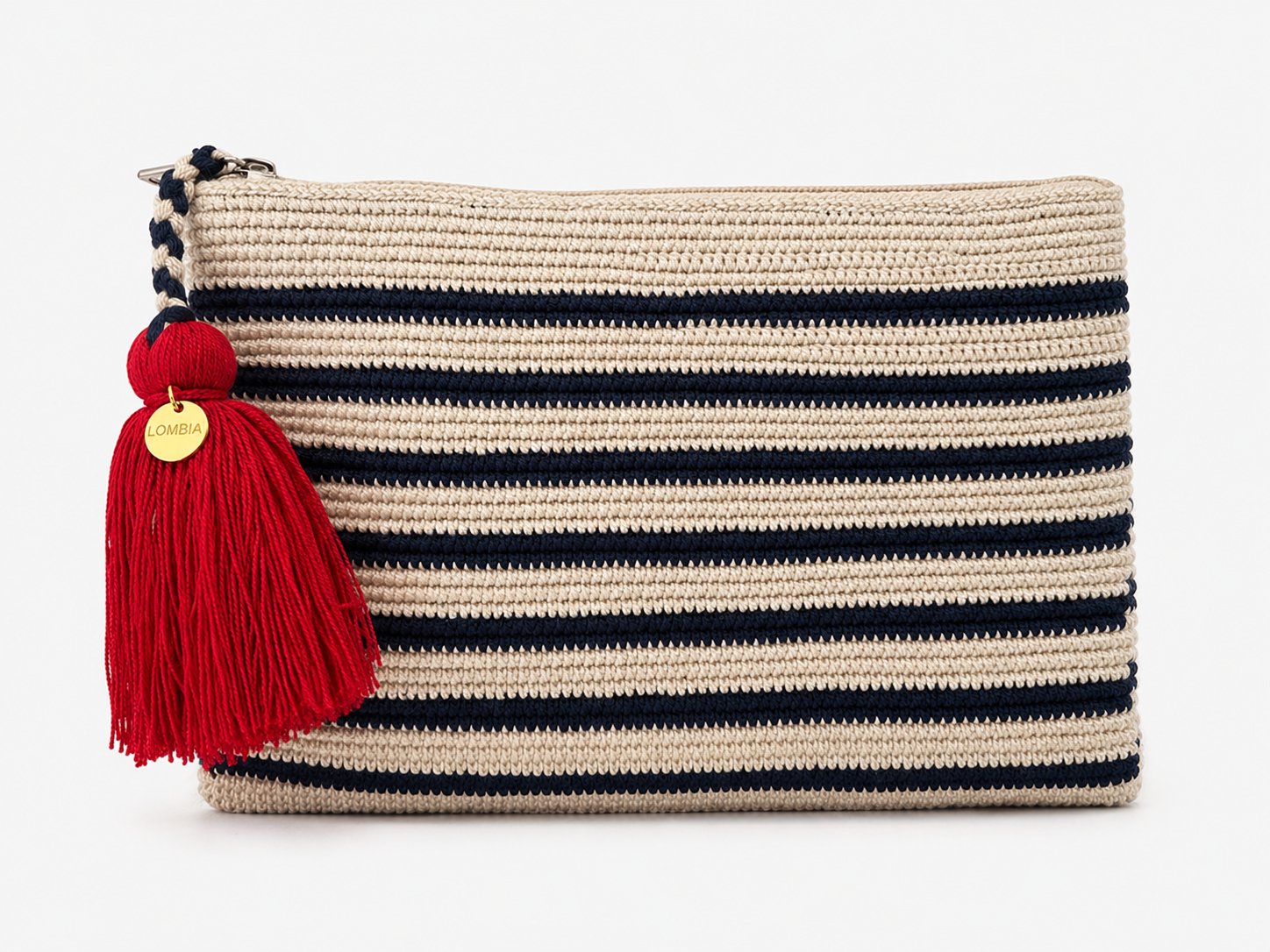 A woven rectangular crochet clutch bag in beige with horizontal stripes in navy blue, featuring a large red tassel with a gold round charm on the zipper pull.